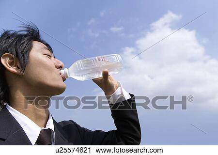 Young businessman drinking a bottle of water under the blue sky, side view, Japan View Large Photo Image Stock Image - Young businessman drinking a bottle of water under the blue sky, side view, Japan. Fotosearch