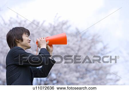 Young businessman holding a megaphone in the field of cherry blossoms, side view, Japan View Large Photo Image Stock Photograph - Young businessman holding a megaphone in the field of cherry blossoms, side view, Japan. Fotosearch