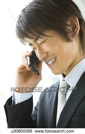 Stock Photograph - Young businessman using a mobile phone, side view. Fotosearch