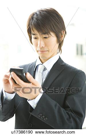 Young businessman using a PDA, front view View Large Photo Image Stock Image - Young businessman using a PDA, front view. Fotosearch