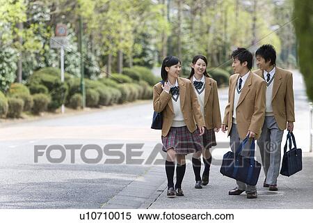 Stock Photography - Four high school students walking on the side of road, smiling, front view, Japan. Fotosearch