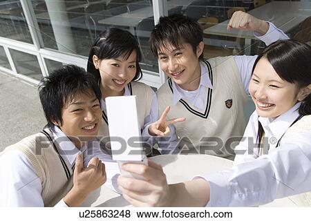 Stock Photo - High school students smiling and photographing with mobile phone, front view, side view. Fotosearch