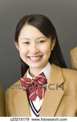 Stock Photo - Portrait of a teenage girl smiling and looking at camera, front view, gray background. Fotosearch