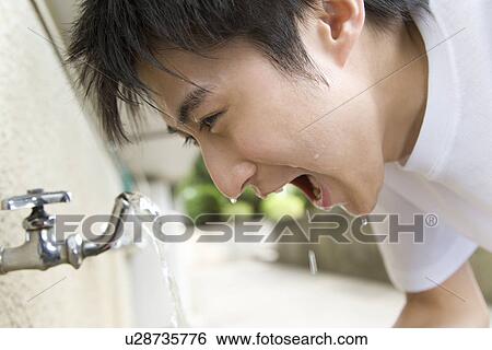 Stock Photograph - Teenage boy in gym cloth washing face, side view. Fotosearch