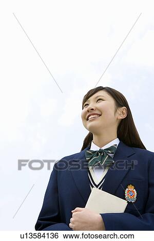 Teenage girl holding a book and looking up at the sky, low angle view, copy space, Japan View Large Photo Image Stock Photograph - Teenage girl holding a book and looking up at the sky, low angle view, copy space, Japan. Fotosearch