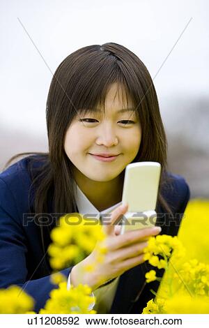 Teenage girl smiling and holding mobile a phone in rape field, front view, Japan View Large Photo Image Stock Image - Teenage girl smiling and holding mobile a phone in rape field, front view, Japan. Fotosearch