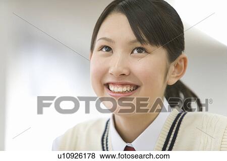 Stock Photo - Teenage girl smiling and looking up, front view. Fotosearch