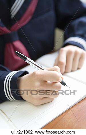 Stock Image - Teenage girl studying at desk, high angle view, close up. Fotosearch