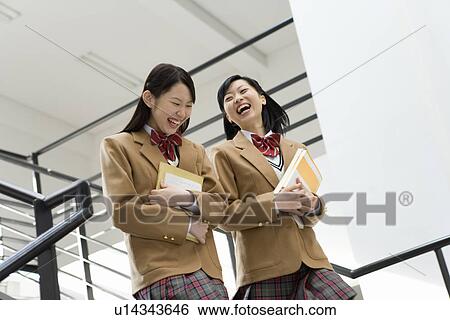 Teenage girls holding text books and walking down the stairs, smiling, low angle view View Large Photo Image Stock Photograph - Teenage girls holding text books and walking down the stairs, smiling, low angle view. Fotosearch