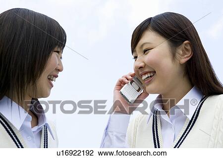 Teenage girls smiling under the blue sky, one using a mobile phone, side view, Japan View Large Photo Image Stock Image - Teenage girls smiling under the blue sky, one using a mobile phone, side view, Japan. Fotosearch