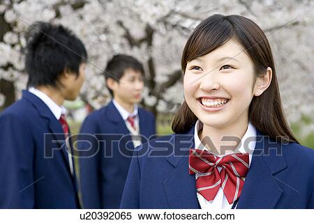 Stock Photography - Three teenagers under cherry trees, smiling, front view, side view, Japan. Fotosearch