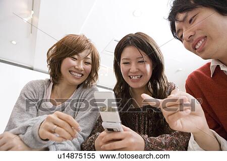 Stock Photography - Three College Students Looking at Cellular Phone. Fotosearch