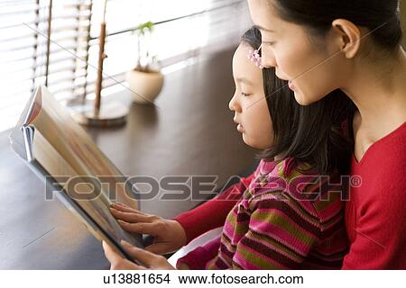 Girl reading a book with mother View Large Photo Image Picture - Girl reading a book with mother. Fotosearch