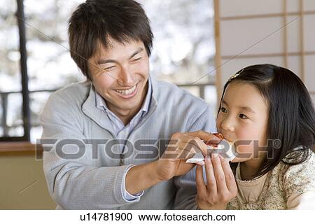 Man feeding daughter pastry, smiling View Large Photo Image Stock Image - Man feeding daughter pastry, smiling. Fotosearch