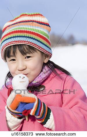 Stock Image - Portrait of a girl kissing snowman, smiling. Fotosearch