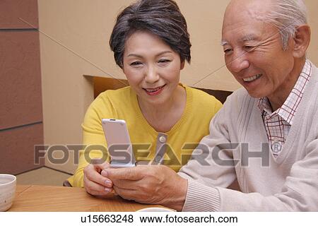 Senior couple looking at a mobile phone, smiling View Large Photo Image Stock Photo - Senior couple looking at a mobile phone, smiling. Fotosearch