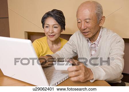 Senior couple using laptop, smiling View Large Photo Image Stock Image - Senior couple using laptop, smiling. Fotosearch