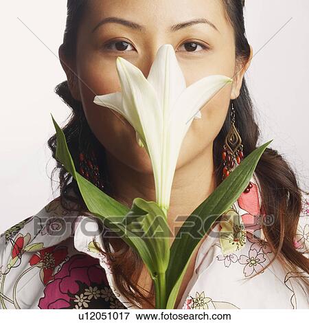 Stock Photo - Close-up of a young woman smelling a flower. Fotosearch