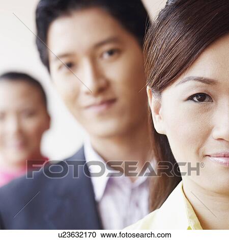Stock Image - Portrait of a businesswoman smiling with her colleagues. Fotosearch