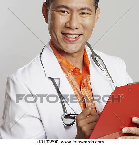 Portrait of a male doctor writing on a clipboard and smiling View Large Photo Image Stock Image - Portrait of a male doctor writing on a clipboard and smiling. Fotosearch