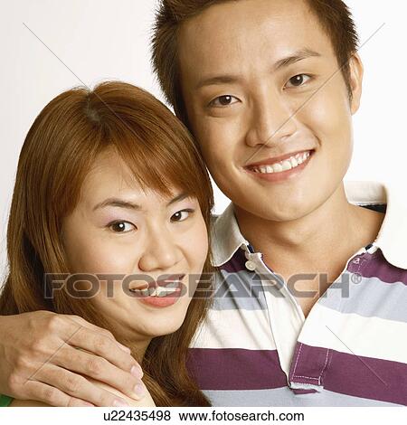 Stock Photo - Portrait of a young couple embracing each other and smiling. Fotosearch
