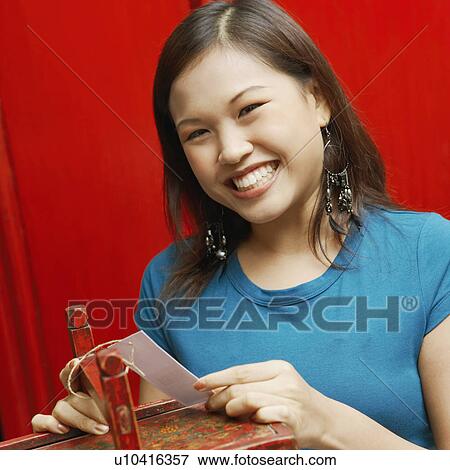 Portrait of a young woman holding a price tag and smiling View Large Photo Image Stock Photo - Portrait of a young woman holding a price tag and smiling. Fotosearch