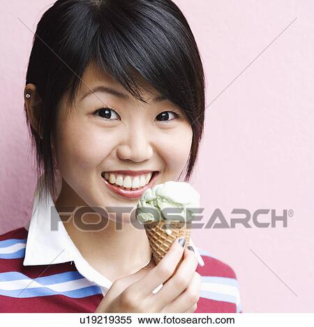 Portrait of a young woman holding an ice-cream cone View Large Photo Image Stock Photography - Portrait of a young woman holding an ice-cream cone. Fotosearch