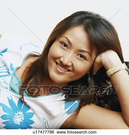 Portrait of a young woman lying on a couch and smiling View Large Photo Image Stock Photograph - Portrait of a young woman lying on a couch and smiling. Fotosearch