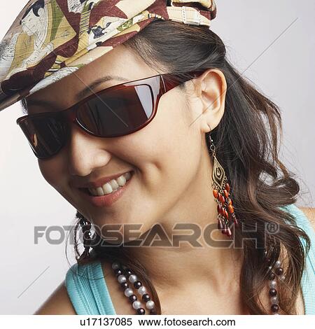 Stock Photography - Portrait of a young woman wearing sunglasses and smiling. Fotosearch