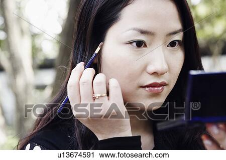 Stock Image - Close-up of a young woman applying make up. Fotosearch