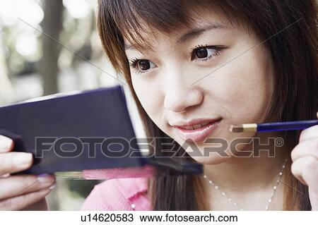 Stock Image - Close-up of a young woman applying make up. Fotosearch