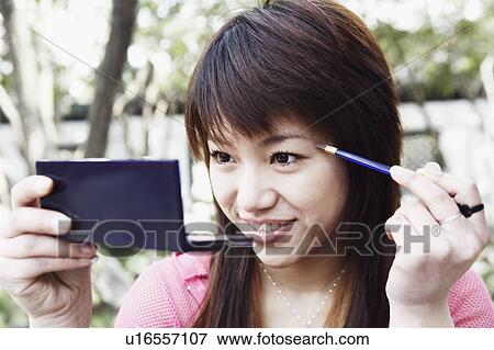 Stock Photo - Close-up of a young woman applying make up. Fotosearch