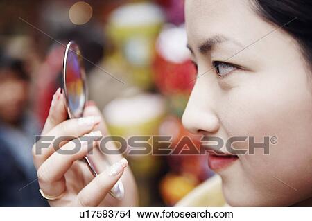 Close-up of a young woman holding a vanity mirror View Large Photo Image Picture - Close-up of a young woman holding a vanity mirror. Fotosearch