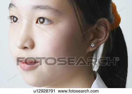 Close-up of a young woman looking away View Large Photo Image Stock Image - Close-up of a young woman looking away. Fotosearch