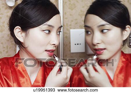 Close-up of a young woman looking in the mirror applying lipstick View Large Photo Image Stock Image - Close-up of a young woman looking in the mirror applying lipstick. Fotosearch