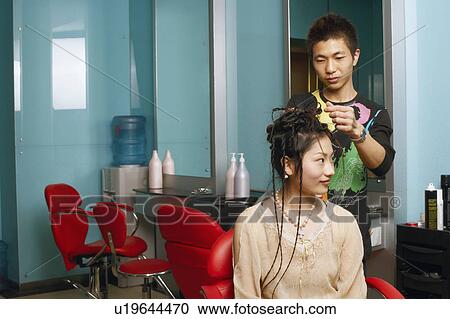 Stock Image - Male hairdresser styling a teenage girl's hair. Fotosearch