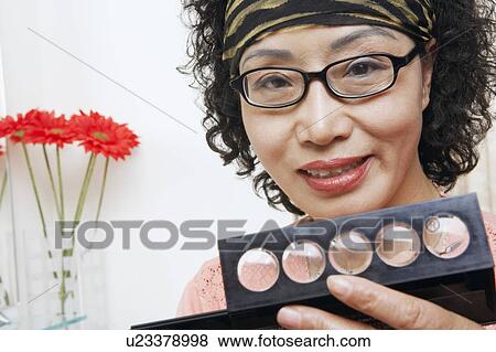 Stock Photo - Portrait of a mature woman holding a make-up kit. Fotosearch
