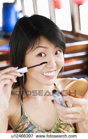 Stock Photo - Portrait of a young woman applying mascara. Fotosearch