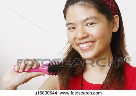 Picture - Portrait of a young woman brushing her hair and smiling. Fotosearch