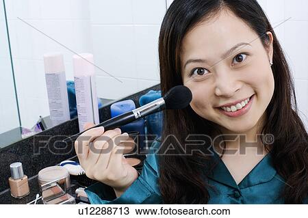 Portrait of a young woman holding a blush brush View Large Photo Image Stock Image - Portrait of a young woman holding a blush brush. Fotosearch