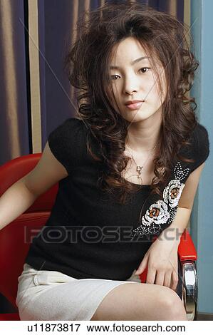 Stock Photo - Portrait of a young woman sitting on an armchair. Fotosearch