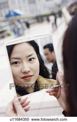 Stock Image - Reflection of a young woman in the mirror. Fotosearch