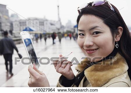Picture - Side profile of a young woman holding a mirror smiling. Fotosearch
