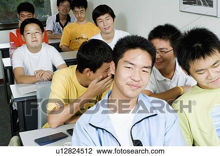 Stock Image - Group of teenage boys sitting in a classroom and smiling. Fotosearch