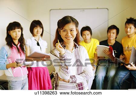 Portrait of a professor smiling with her students in a classroom View Large Photo Image Stock Image - Portrait of a professor smiling with her students in a classroom. Fotosearch