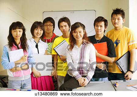 Stock Photo - Portrait of a professor smiling with her students in a classroom. Fotosearch