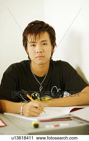 Stock Image - Portrait of a teenage boy holding a pen on a notepad. Fotosearch