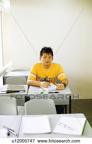 Portrait of a young man writing on a notepad in the classroom View Large Photo Image Stock Photo - Portrait of a young man writing on a notepad in the classroom. Fotosearch