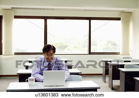 Stock Image - Senior man sitting on a chair and using a laptop. Fotosearch