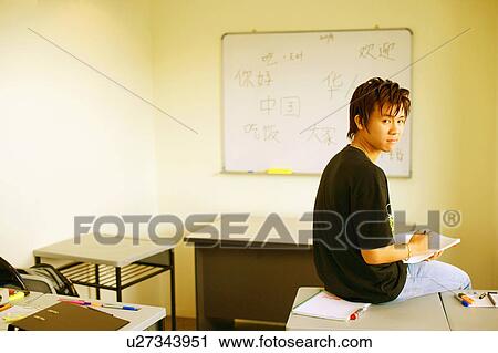 Side profile of a teenage boy sitting on a desk in a classroom View Large Photo Image Stock Image - Side profile of a teenage boy sitting on a desk in a classroom. Fotosearch